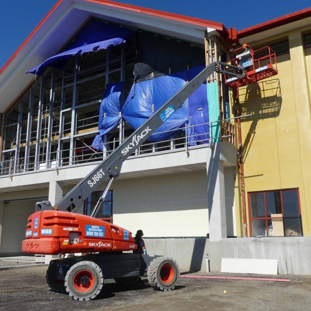 Straight telescopic boom lift being used on a commercial building site for high-reach exterior access work