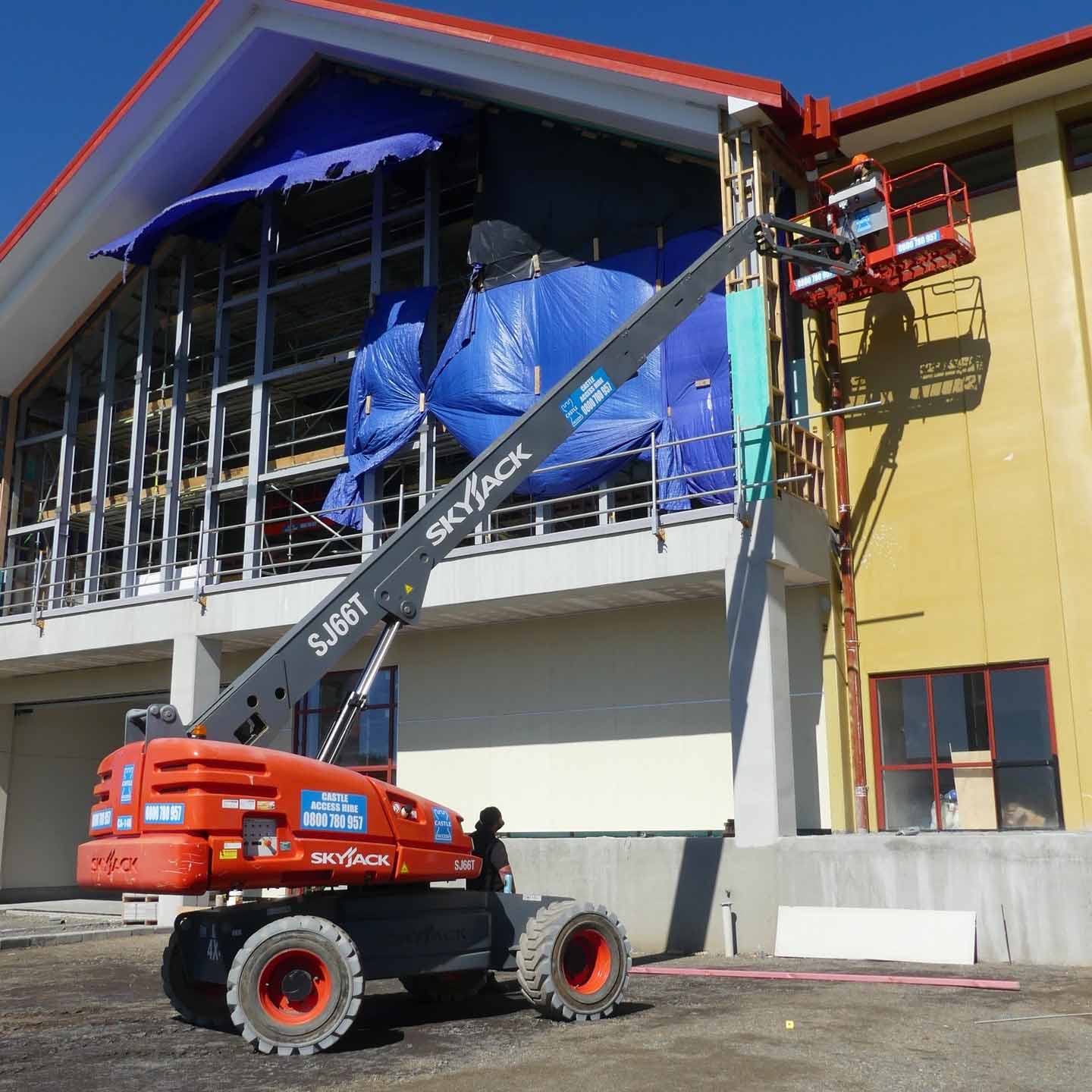 Straight telescopic boom lift being used on a commercial building site for high-reach exterior access work
