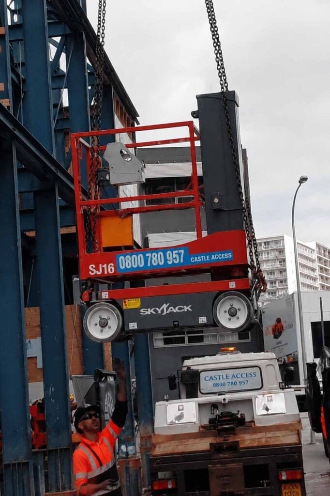 Compact scissor lift being used for building maintenance and access work on a busy urban site